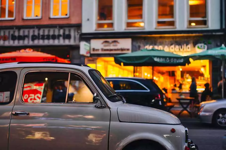 grey car in foreground with local businesses in the background